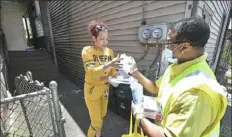  ?? Peter Diana/Post-Gazette ?? Community health deputy John Burwell hands gloves and face masks to Carol Kovac on Monday in Braddock.