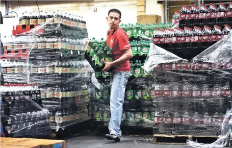  ??  ?? Ernesto Mendoza, an employee at The Coca-Cola Bottling Co. of Santa Fe, carries soft drinks to a pallet on Wednesday. Mendoza worries about the possibilit­y of a sugar tax that Mayor Javier Gonzales wants to impose on the very products that pay his...