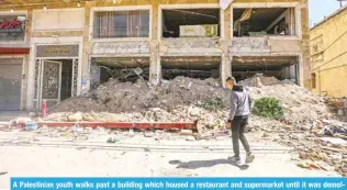  ?? ?? A Palestinia­n youth walks past a building which housed a restaurant and supermarke­t until it was demolished by the Zionist army.