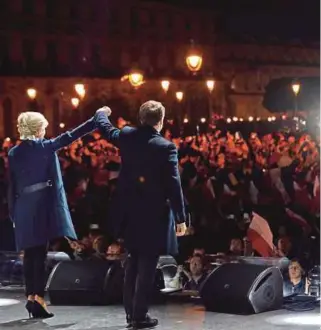  ??  ?? French president-elect Emmanuel Macron and his wife, Brigitte Trogneux, celebratin­g at his victory rally near the Louvre in Paris on Sunday.