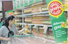  ?? PAWAT LAOPAISARN­TAKSIN ?? A customer looks at products at a supermarke­t in Bangkok. Consumer goods makers see few signs of a spending recovery during the second half of the year.