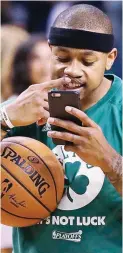  ??  ?? Boston Celtics star Isaiah Thomas looks at his teeth using a cellphone prior to the start of their NBA playoff game with the Washinton Wizards. Thomas went on to score 53 points as the Celtics won in overtime, 129-119. (AP)