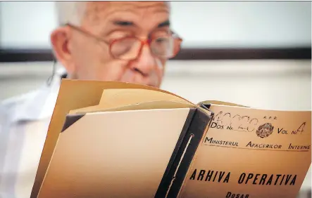  ?? THE ASSOCIATED PRESS ?? A man who refused to be identified by name reads a communist-era secret police file in Bucharest, Romania. The country’s secret police kept a large file on Katherine Verdery, who recounts in her memoir that she was doing research on Romanian village life in the 1970s and ’80s.