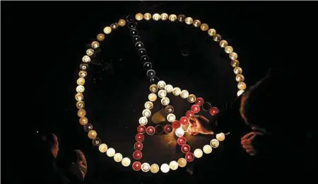  ?? Laurent Cipriani / Associated Press ?? People, above, light candles at the Place de la Republique in Paris on Friday after French artists and cultural figures called for people to mark a week since the start of the Paris attacks with an outpouring of “noise and light.” French President...