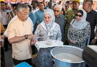  ?? ?? Sultan abdullah and Tunku azizah scooping bubur lambuk for sampling when they visited the Tanjong Tokong Ramadan Bazaar in april. also present were yang di-pertua negeri Tun ahmad Fuzi abdul Razak (second, right) and his wife Toh Puan Khadijah Mohd nor (right). — Bernama