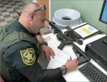  ?? BEN DICKMANN VIA AP ?? In this photo provided by Ben Dickmann, a deputy at the Broward County sheriff’s office in Ft. Lauderdale, Fla., processes paperwork to take possession of and destroy Dickmann’s AR-style firearm. Dickmann decided to turn in his weapon after the...