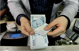  ?? — AFP ?? An exchange office worker counts Turkish lira banknotes in Istanbul.