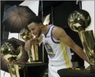  ?? JEFF CHIU — THE ASSOCIATED PRESS ?? Golden State Warriors’ Stephen Curry squints as he looks into a trophy while posing for photos for the team’s photograph­er during media day at the NBA basketball team’s practice facility in Oakland Monday.