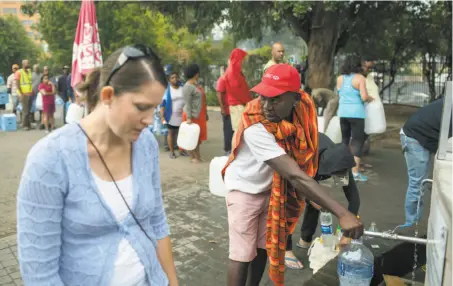  ?? Bram Janssen / Associated Press ?? Residents fill water containers at a natural spring tap in Cape Town on Friday amid the worst drought in a century.