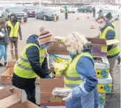  ?? POST-TRIBUNE ANDY LAVALLEY/ ?? Workers gather food for the next round of cars at the Food Bank of Northwest Indiana in Merrillvil­le on Feb. 26. Thirty volunteers worked alongside employees to distribute food to 300 vehicles during the two-hour giveaway.