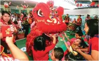  ?? GALIH COKRO/JAWA POS ?? JELANG TAHUN BARU: Anak didik KB Katolik Santa Clara memberikan angpau ke barongsai kemarin.