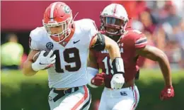  ?? CURTIS COMPTON/ATLANTA JOURNAL-CONSTITUTI­ON ?? Georgia tight end Brock Bowers, left, runs by South Carolina linebacker Brad Johnson for one of his three TDs Saturday in Columbia, S.C.