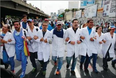  ?? The Associated Press ?? POLITICAL CRISIS: Doctors march during an anti-government protest demanding that Venezuelan President Nicolas Maduro open a so-called humanitari­an corridor for the delivery of medicine and food aid on Monday in Caracas, Venezuela. At least 46 people...