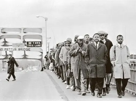  ?? Alabama Department of Archives via Magnolia Pictures ?? John Lewis, right, marches with fellow protesters at the Edmund Pettus Bridge in Selma, Ala. In what came to be known as Bloody Sunday, a trooper cracked Lewis’ skull with a billy club, knocking him to the ground, then hit him again when he tried to get up.