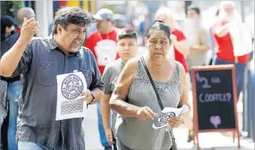  ??  ?? LEONARDO VILCHIS SR., left, director of Union de Vecinos, hands out fliers urging a boycott of Weird Wave. “It’s a threat to local businesses and it’s one more sign of gentrifica­tion that we need to defeat,” he said.