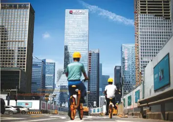  ?? Reuters ?? ■ Men ride bicycles past constructi­on sites near the headquarte­rs of China Evergrande Group in Shenzhen, Guangdong province, China.