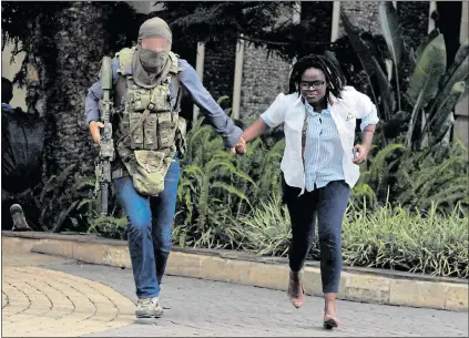  ?? Picture: NJERI MWANGI/Reuters ?? RESCUED: A survivor is guided to safety by the SBS hero at the hotel in Nairobi where 21 were killed