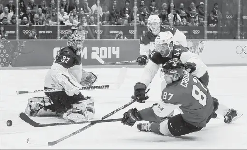  ?? Petr David Josek/Associated Press photos ?? Penguins teammates duel as Canada’s Sidney Crosby shoots against U.S. defenseman Brooks Orpik in the third period of the Olympic semifinal in Sochi, Russia.