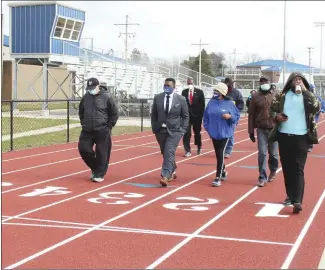  ?? Katie West • Times-Herald ?? Forrest City School District Superinten­dent Dr. Tiffany Hardrick, center, talks with Deputy Superinten­dent Dr. Zrano Boles while taking the first lap around the district’s new six-lane track with other school district employees and members of the community. District officials held a ribbon cutting for the track on Tuesday. The facility is scheduled to be available for public use from 5:45 to 6:45 each weekday morning and evening, with hours possibly changing for public usage on weekends.