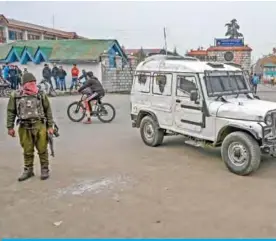  ?? — AFP ?? KASHMIR: A security personnel (left) stands near the site of a grenade blast at a market place outside the campus of Kashmir’s main university in Srinagar yesterday.