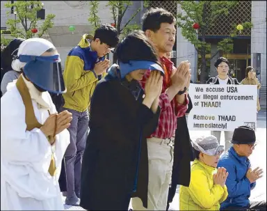  ?? AP ?? South Korean protesters pray during a rally to oppose a plan to deploy the advanced US missile defense system near the US embassy in Seoul, South Korea on Thursday.