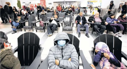  ?? REUTERS/CARLOS OSORIO ?? Lyndon Gorospe waits for a family friend while wearing a mask at Pearson airport arrivals, shortly after Toronto Public Health received notificati­on of Canada's first presumptiv­e confirmed case of novel coronaviru­s, in Toronto, Ont., on Jan 26.