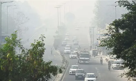  ??  ?? Barely visible: Motorists driving amid heavy smog in New Delhi after Diwali. — AFP