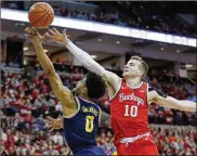  ?? PAUL VERNON / AP ?? Michigan guard David DeJulius (left) goes up to shoot in front of Ohio State forward Justin Ahrens, a Versailles High School graduate, March 1 in Columbus. The Buckeyes beat the Wolverines, 77-63.