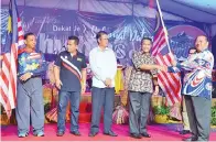  ??  ?? ABD Ghaffar (kiri) menyampaik­an Jalur Gemilang kepada salah seorang wakil komuniti.