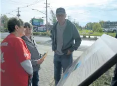  ??  ?? Event-goers take a moment to read the newly installed Niagara, St. Catharines & Toronto Railway Plaque at the railway's former Stop 19 site in Welland Monday morning.