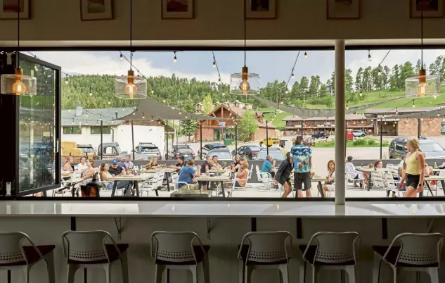  ?? Andy Colwell, Special to The Denver Post ?? Patrons of Campfire enjoy the patio, as seen through the restaurant’s open window-wall on a warm Saturday.