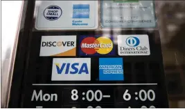  ?? MATT ROURKE — THE ASSOCIATED PRESS ?? Credit card options are shown on a store's door in 2018in Philadelph­ia. Noticeable pockets of Americans quickly are running up credit card balances and falling behind on their debts.