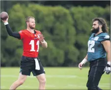  ?? MEDIANEWS GROUP PHOTO ?? Carson Wentz warms up while Jason Kelce walks by during an Eagles practice recently. Wentz is in the corner of his friend and tight end Zach Ertz, who is having a contract squabble with management.