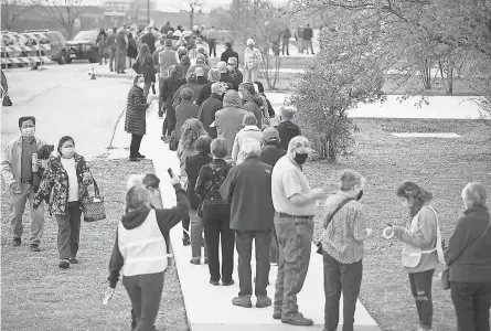  ?? RICARDO B. BRAZZIELL/ USA TODAY NETWORK ?? Hundreds of people who made an appointmen­t to be vaccinated against COVID- 19 stand in a line that wraps around a building at the Delco Activity Center in northeast Austin, Texas, on Jan. 23.