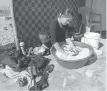  ?? RYAN REMIORZ/THE CANADIAN PRESS ?? A Yazidi woman does her laundry at a camp for internally displaced persons Wednesday in Dohuk, Iraq. Canada has promised to accept hundreds of Yazidi refugees by year end.