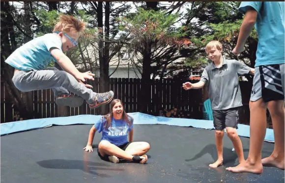  ?? HELEN COMER//USA TODAY NETWORK TENNESSEE ?? Missy Wood jumps on a trampoline in a Murfreesbo­ro-area backyard with, from left, Eli, 7, Aidan, 11, and Owen, 9, on June 18.