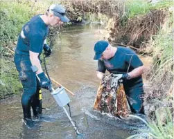  ?? Photo: TRACEY ROBINSON/FAIRFAX NZ ?? Dirty work: Police divers Constable Paul Ferguson and Senior Sergeant Brice Adams search a stream for the sawn-off .22 calibre rifle thought to have been used in the 1976 ANZ Bank robbery.