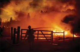  ?? NOAH BERGER — THE ASSOCIATED PRESS ?? A firefighte­r extinguish­es flames as the Oak fire crosses Darrah Road in Mariposa County on Friday. Crews were able to to stop it from reaching an adjacent home.