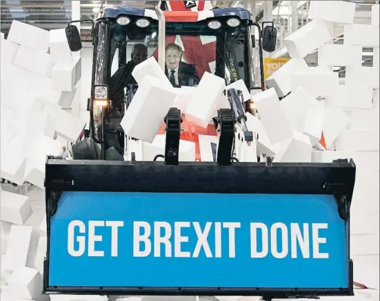  ?? STEFAN ROUSSEAU / AP ?? El líder conservado­r, Boris Johnson, rompe un muro de espuma con su eslogan de partido, Get Brexit Done (Hagamos el Brexit de una vez)