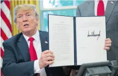  ?? PABLO MARTINEZ / THE ASSOCIATED PRESS ?? U.S. President Donald Trump holds up the executive order he signed to end separation­s among families that are detained after crossing the U.S. border illegally.