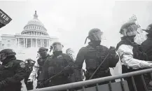  ??  ?? Police stand guard Jan. 6 after holding off rioters who tried to break through a barrier at the Capitol in Washington.