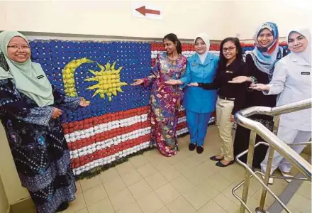  ?? PIC BY MOHD SYAFIQ RIDZUAN AMBAK ?? Dr Wan Nazihah Wan Abu Bakar (left) and her staff used egg trays, rags and old newspapers to make the Jalur Gemilang at the Bukit Payong Dental Clinic in Marang.