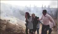  ??  ?? Palestinia­ns run away from tear gas fired by Israeli forces during clashes over an order to shut down a Palestinia­n school in the town of As-Sawiyah, south of Nablus in the occupied West Bank, yesterday.