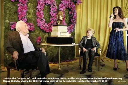  ?? Chris Pizzello ?? > Actor Kirk Douglas, left, looks on as his wife Anne, center, and his daughter-in-law Catherine Zeta-Jones sing Happy Birthday during his 100th birthday party at the Beverly Hills Hotel on Decemeber 9, 2016