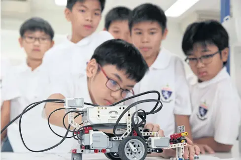  ?? WEERAWONG WONGPREEDE­E ?? Students at King Mongkut’s Internatio­nal Demonstrat­ion School operate a robot they developed as a teaching tool to make learning more fun.