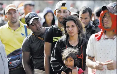  ?? Gregory Bull ?? The Associated Press Marvin Ochoa, center, of Honduras, waits in line for a meal behind his wife, Diana Marylin Ochoa, after they arrived with a Central America migrant caravan Thursday in Tijuana, Mexico.