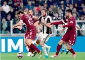  ?? — AFP ?? Juventus’ Gonzalo Higuain vies with Torino’s Emiliano Moretti and Marco Benassi in Turin on Saturday.