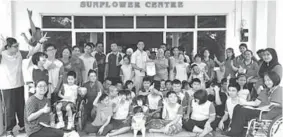  ??  ?? Wan (standing, centre) hands over a souvenir to the person-in-charge of Sunflower Centre.