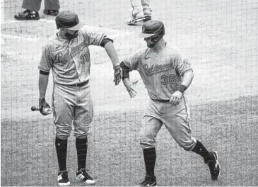  ?? MANUEL BALCE CENETA/AP ?? The Orioles’ Renato Núñez congratula­tes teammate Bryan Holaday with an elbow bump after scoring a run on Anthony Santander’s two-run single during the fifth inning against the Nationals in Washington on Sunday.