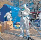  ?? BLOOMBERG ?? Workers in protective gear dismantle a temporary shelter outside a neighbourh­ood placed under lockdown due to Covid in Beijing.